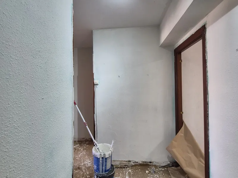 Pasillo de la vivienda en obra, con el suelo protegido y las paredes sin acabar