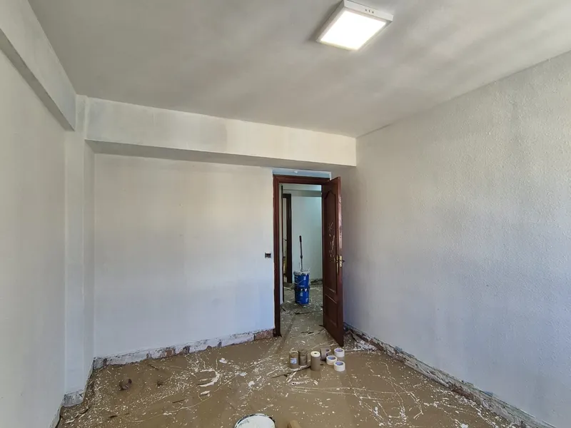 Habitación en obra con el suelo cubierto y la carpintería retirada