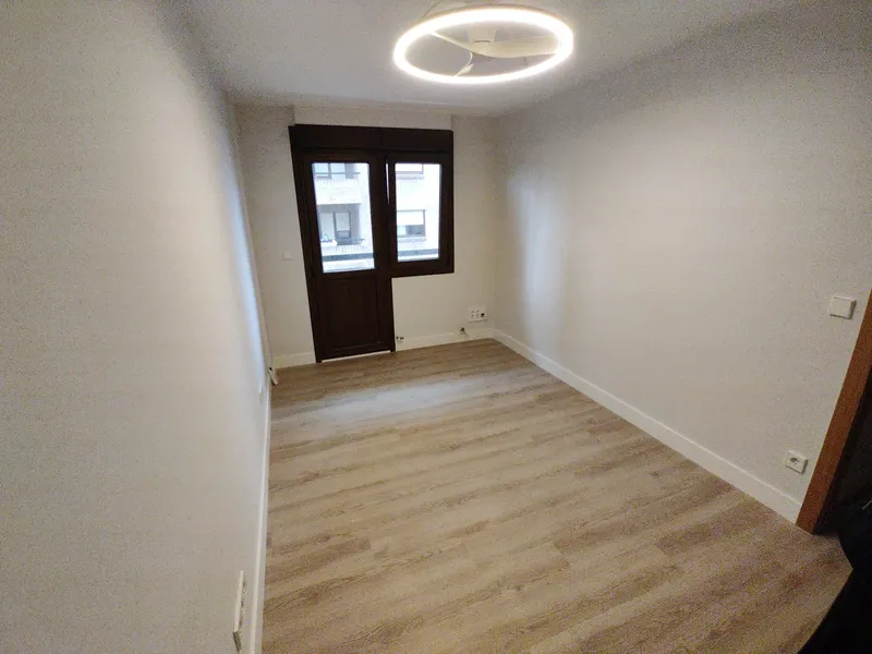 Habitación terminada con suelo de madera y luminaria circular