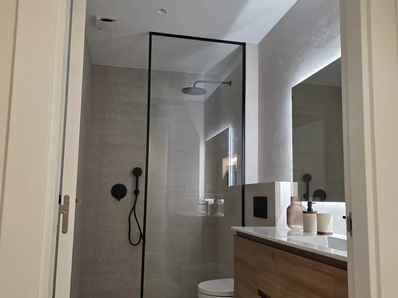 Baño terminado visto desde la puerta, con espejo retroiluminado